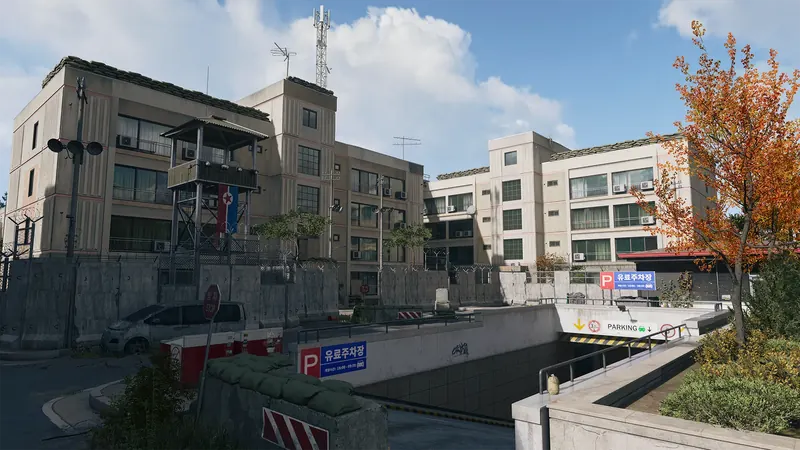 A fortified residential compound with a guard tower, barbed-wire fencing, and an underground parking entrance.